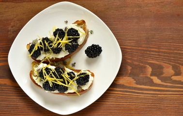 Crostini with goat cheese, blackberries, lemon zest and honey, top view, copy space