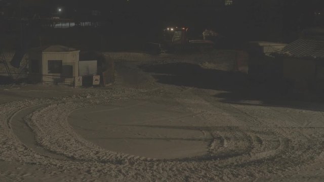 BELOKURIKHA, RUSSIA - MARCH 8, 2018: Red ratrak clears snow in the ski resort at night. A strong snowstorm on the mountainside. S-log, ungraded, no color.