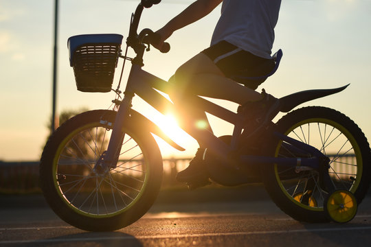 Little boy riding bike at sunset. Child on bicycle into the sun