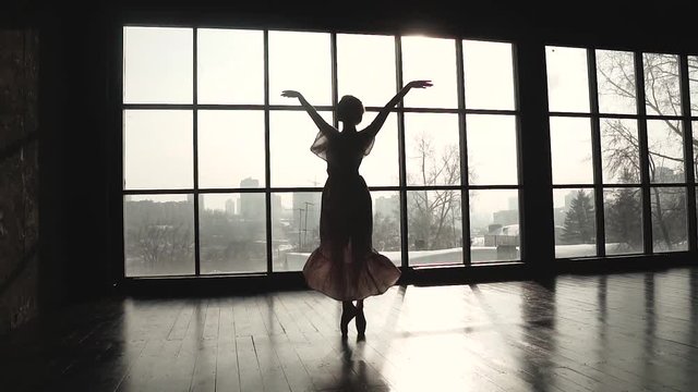 The silhouette of a ballerina swirling on tiptoes in pointe shoes and a long fluttering dress. Ballet dancer dances ballet. slow motion