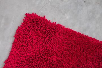Gray concrete floor with red rug fluffy carpet from above. Modern minimal industrial bedroom or...