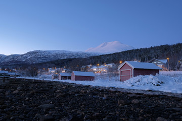 Landscape of Norway in winter during blue hour. Norwegian coastline in winter. Mountain covered with snow at the background.