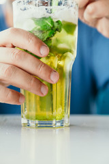 man is holding tall glass with cocktail on table