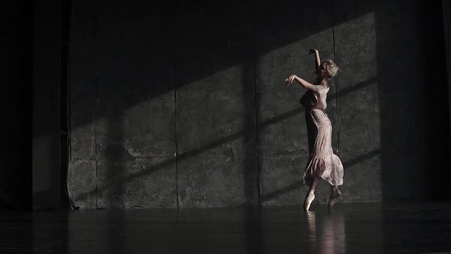 a ballet dancer in pointe shoes and a long fluttering dress is spinning on tiptoes and elegantly moving. slow motion