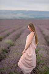Fototapeta na wymiar Happy family in a field of lavender on sunset. Mom and girl walk on the lavender field.