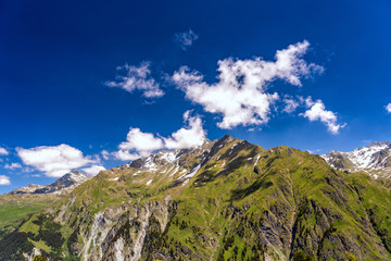Obraz premium Scenic view of beautiful landscape in Swiss Alps. Fresh green meadows and snow-capped mountain tops in the background in springtime, Switzerland.