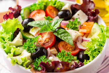 Fresh Greek salad with vegetables, feta cheese and black olives in white bowl on purple wooden background