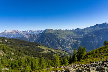 Obraz premium Scenic view of beautiful landscape in Swiss Alps. Fresh green meadows and snow-capped mountain tops in the background in springtime, Switzerland.
