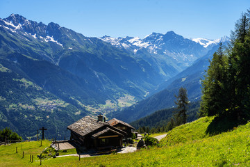 Scenic view of beautiful landscape in Swiss Alps. Fresh green meadows and snow-capped mountain tops...