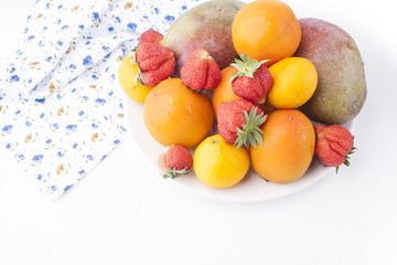 Different fruits on a white background, apricots, mangoes and berries. Free space for text. Top view