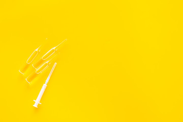 Flu vaccination concept. Syringe and ampoulie on yellow background top view copy space