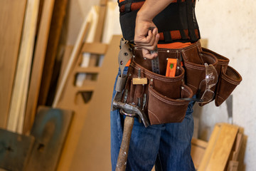 Man with tool belt in a workshop - obrazy, fototapety, plakaty