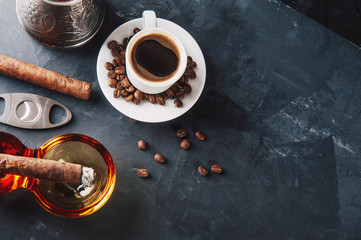 Cup of coffee, coffee beans, ashtray with cigar on dark background