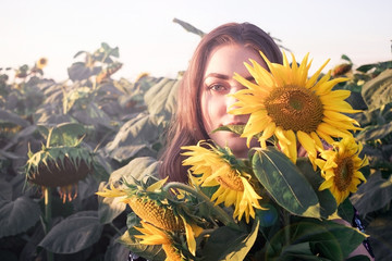 Young girl with sunflowers in the bright sun