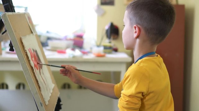 Boy painting picture with oils during art class