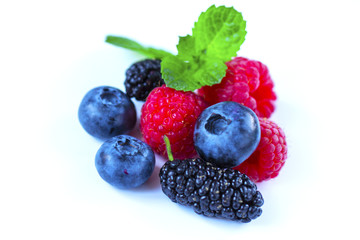 Close-up arrangement mixed, assorted berries including blackberries, strawberry, blueberry, raspberries and fresh leaf on white