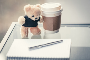 Hot coffee cup with teddy bear and diary