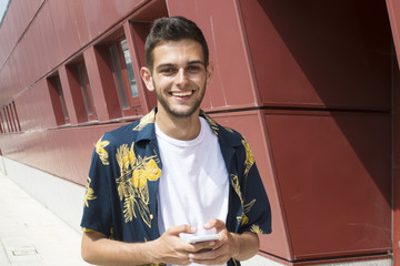 young man with mobile phone walking down the street
