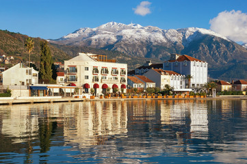 Fototapeta na wymiar Sunny winter Mediterranean landscape. Montenegro, embankment of Tivat city and snow-capped peaks of Lovcen mountain