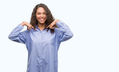 Young hispanic business woman looking confident with smile on face, pointing oneself with fingers proud and happy.