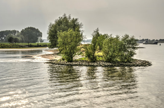 Little peninsula, with sandy and rocky beaches as well as shrubs and low trees, in the river Waal, near Brakel, the Netherlands