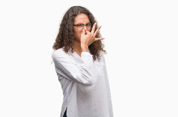 Fototapeta premium Beautiful young hispanic woman smelling something stinky and disgusting, intolerable smell, holding breath with fingers on nose. Bad smells concept.