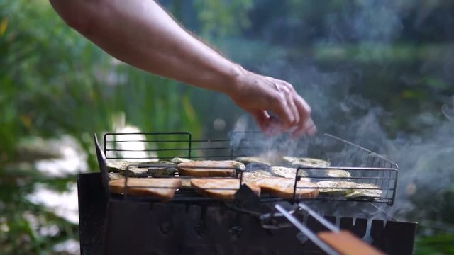 man bakes bread and vegetables on barbecue outdoor