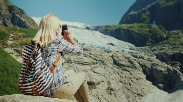 Woman tourist taking pictures of the glacier. Traveling in Norway concept