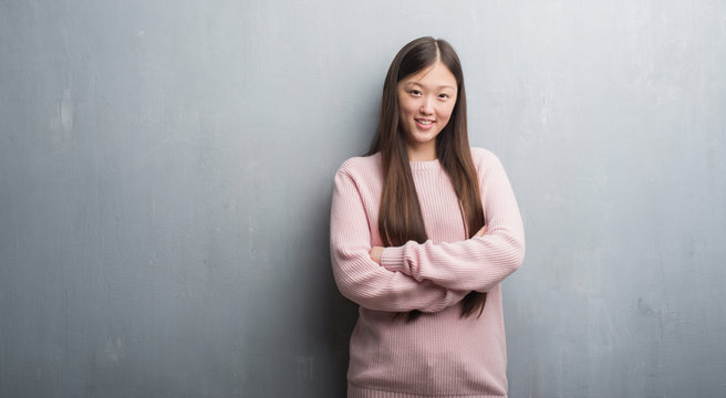 Young Chinese woman over grey wall happy face smiling with crossed arms looking at the camera. Positive person.