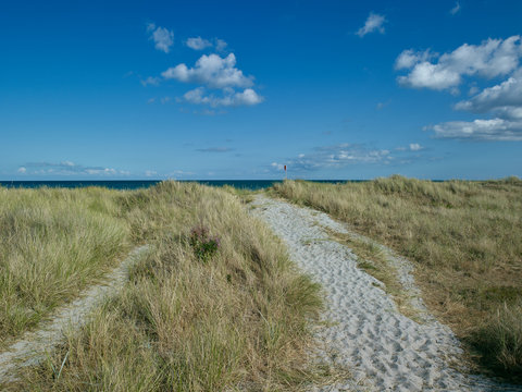 Laesoe / Denmark: Red flag on the edge of a small sandy footpath through the dunes at Bloeden Hale
