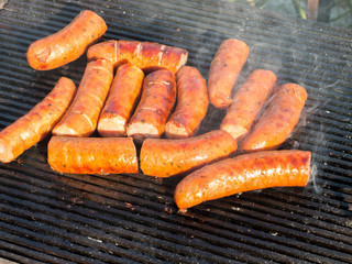 delicious sausages frying on grill