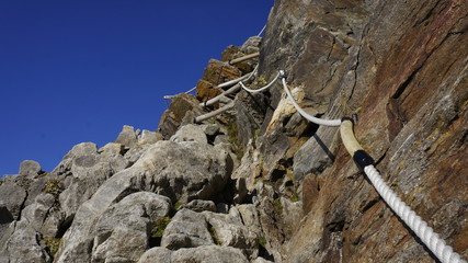 Zabezpieczony linami szlak po skalnej ścianie w alpach.