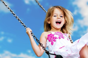 Little child blond girl having fun on a swing