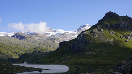 Naklejka na ściany i meble Alpejski wysokogórski lodowcowy krajobraz z skalista górą na pierwszym planie.