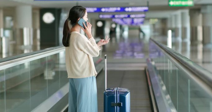 Woman talk to cellphone with her luggage in the airport
