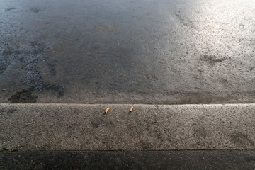 zwei Zigarettenkippen auf schmutzigem Asphalt - obrazy, fototapety, plakaty