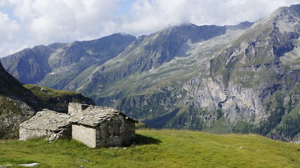 Górska chata pokryta granitowymi płytami na stoku górskim na tle doliny.