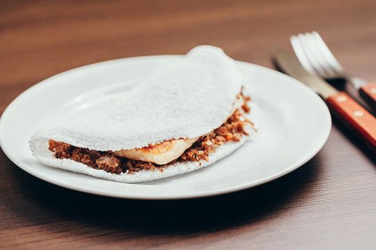 Brazilian Tapioca with cheese (coalho) over a wooden table