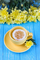 Lemon tea and yellow chrysanthemums on a blue background. Free space