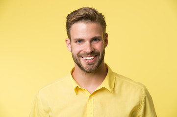 Brilliant smile. Man smiling face posing confidently yellow background. Man shop consultant looks cheerful confident and hospitable. Guy with bristle glad to help you in shop. Sincere emotions