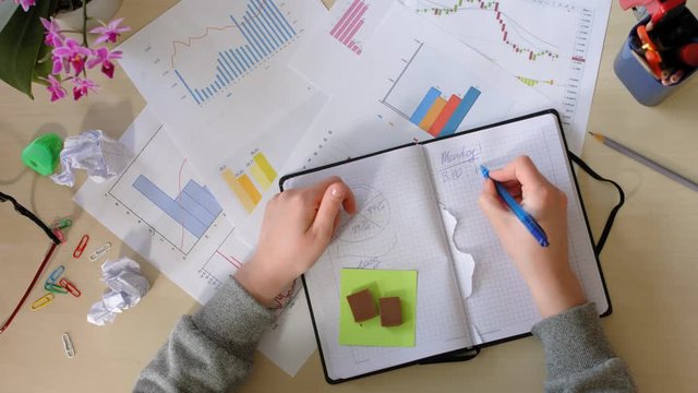 Girl makes notes in a notebook, gets angry and tears out pages. Top view.