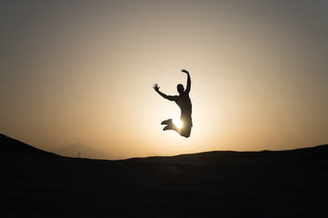 Achieve main goal. Silhouette man motion jump in front of sunset sky background. Future success...