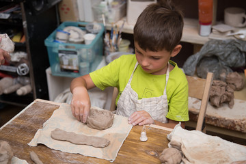 Pottery workshop for kids, raw clay, sculpting tools, glazing and painting clay pots