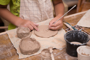 Pottery workshop for kids, raw clay, sculpting tools, glazing and painting clay pots
