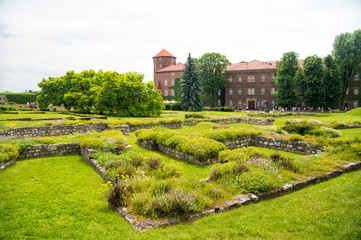Fototapeta na wymiar Luxury estate with big green garden. Elite apartments concept. Estate for aristocracy or old castle in Krakow. Castle with tower made out of red brick surrounded lawns and trees. Luxury architecture