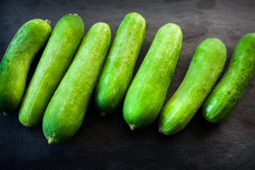 Group of whole baby cucumbers on a grey slate plate