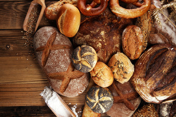 Different kinds of bread and bread rolls on board from above. Kitchen or bakery