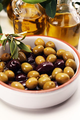 Olives. Bottle virgin olive oil and oil in a bowl with some olives