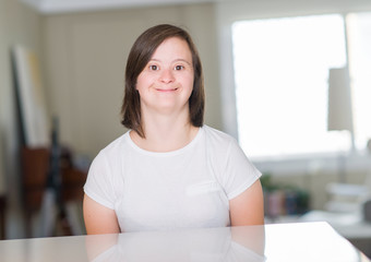 Down syndrome woman at home with a happy face standing and smiling with a confident smile showing...