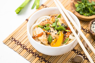 Udon stir-fry noodles with chicken and vegetables on white.